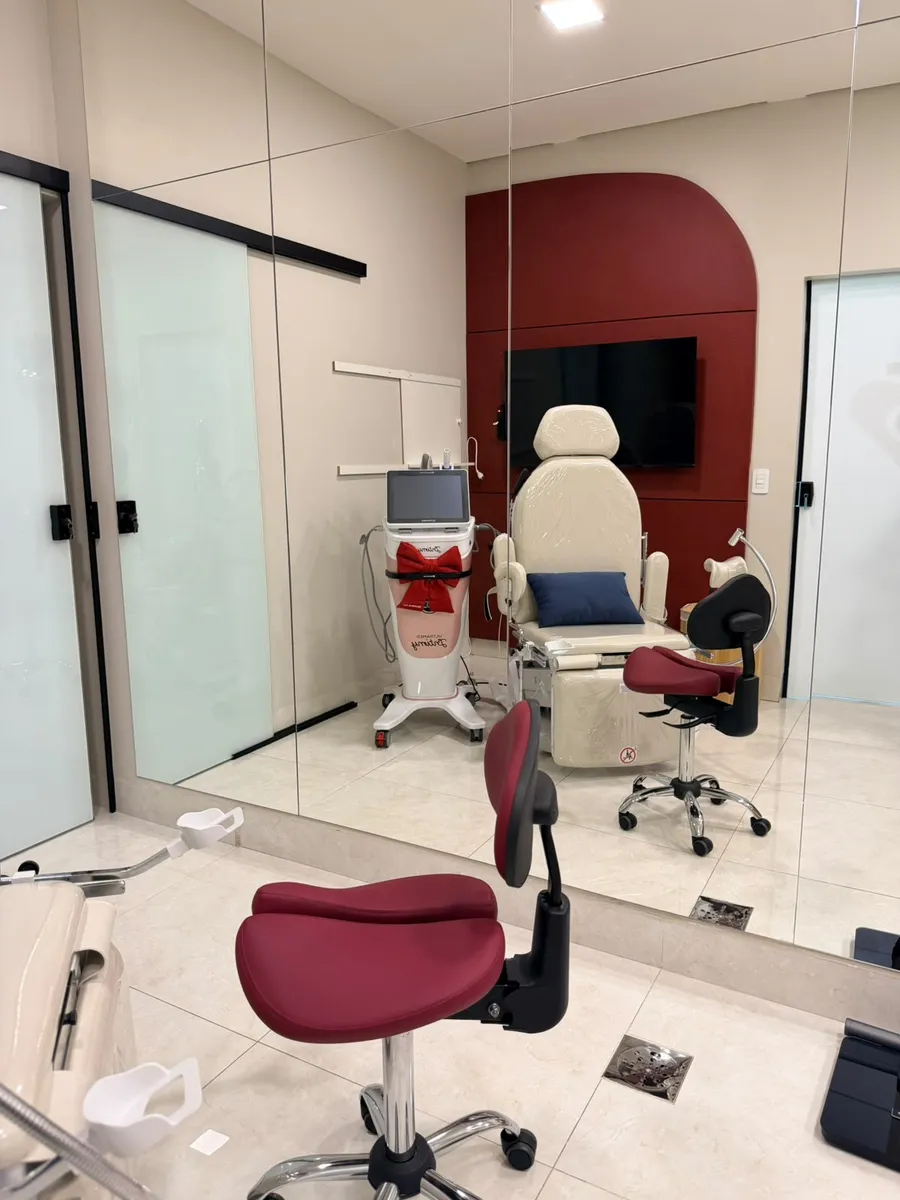 Cadeira ginecológica e equipamentos na sala de exames do consultório
